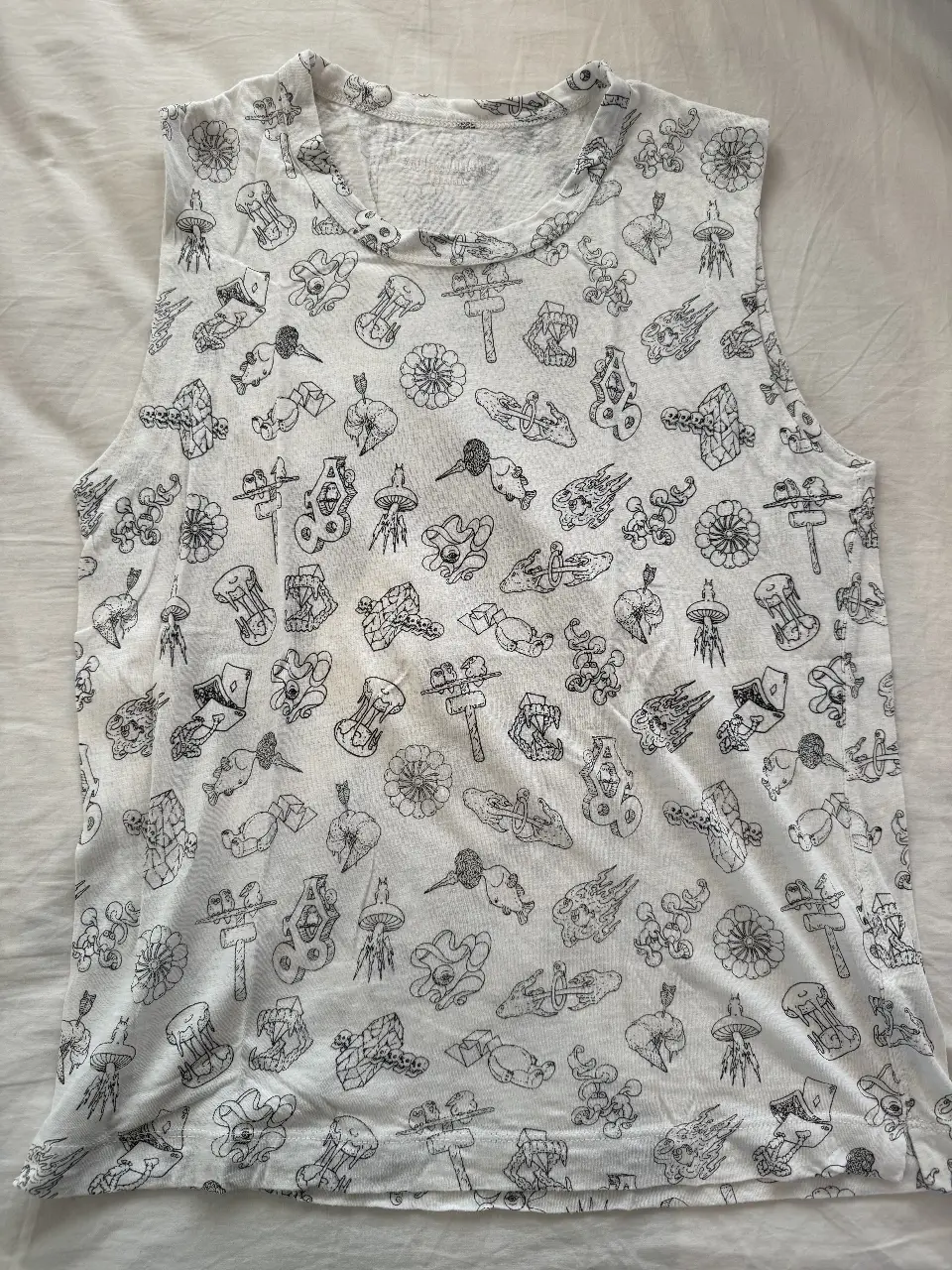 Musculosa blanca con estampado repetitivo en negro. Ideal para un look casual y fresco.