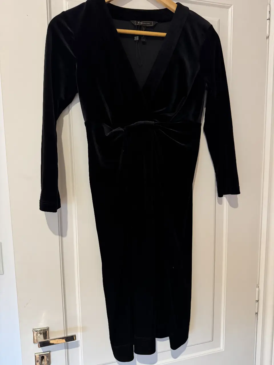 Vestido midi de terciopelo negro, con escote en V y detalle fruncido en la cintura. Ideal para eventos formales o fiestas.