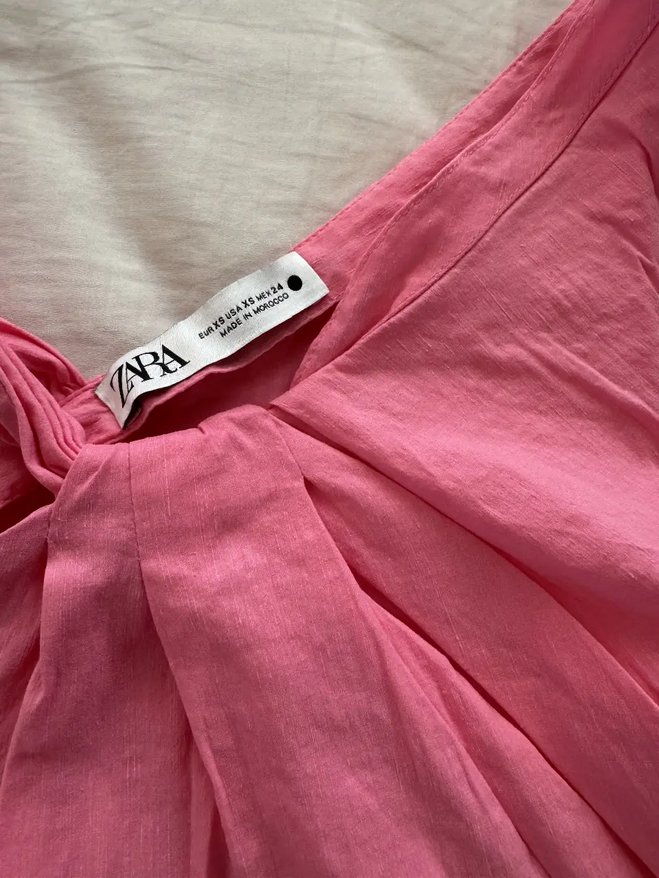 Blusa rosa de Zara, con un diseño asimétrico y detalle fruncido en el frente. Ideal para un look moderno y femenino.