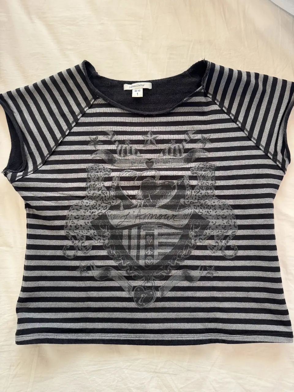Remera a rayas horizontales en tonos grises y negros. Diseño con un estampado central y mangas cortas. Ideal para un look casual y moderno.