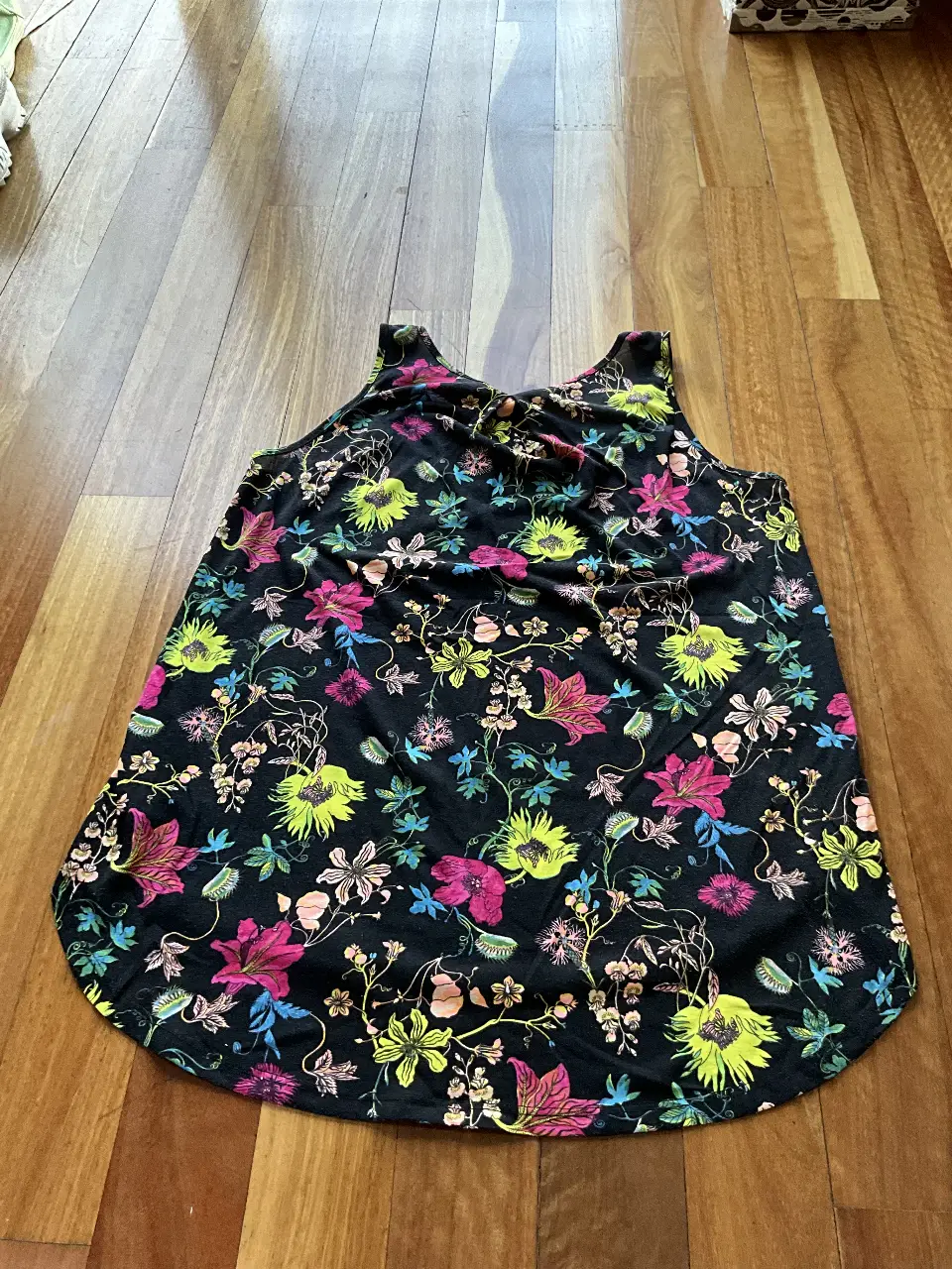 Musculosa de mujer con estampado floral en tonos vibrantes sobre fondo negro. Ideal para un look fresco y casual.