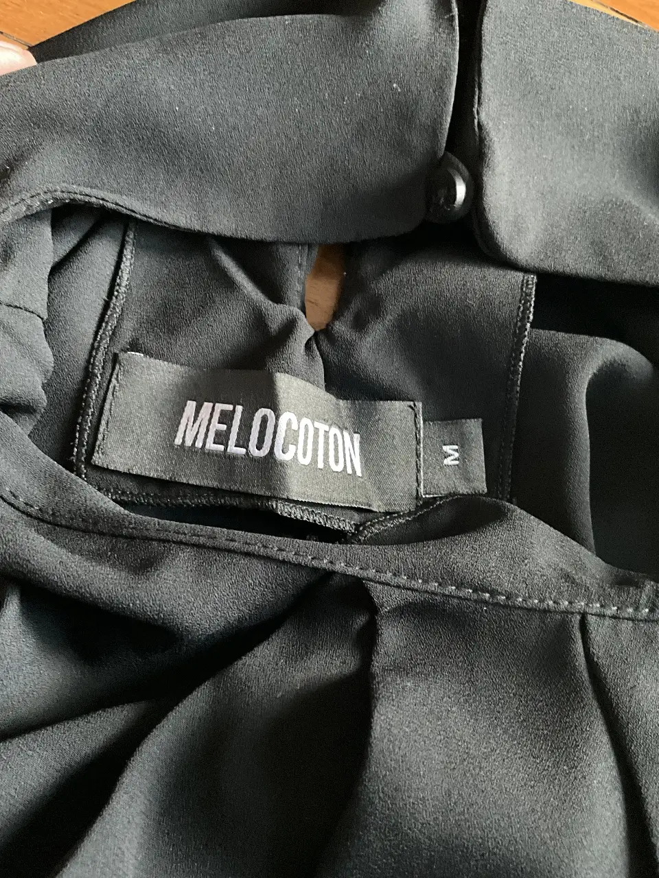 Blusa negra de manga larga con cuello alto y detalle de botón en la parte trasera. Ideal para un look elegante y sofisticado.