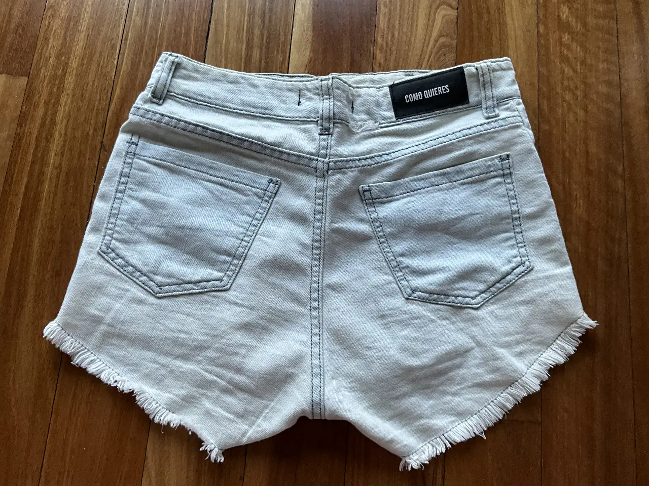 Short de jean tiro alto de mujer, con flecos en el borde inferior. Marca Como Quieres. Talle 38.