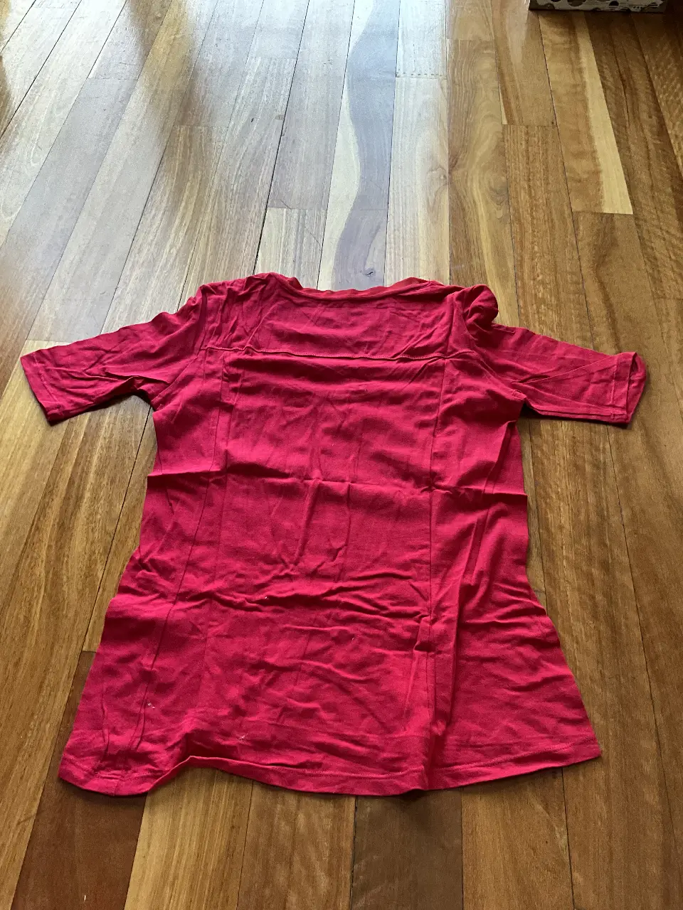 Remera roja de manga corta, con cuello redondo y detalle de tela mesh en el cuello. Ideal para un look casual y cómodo.