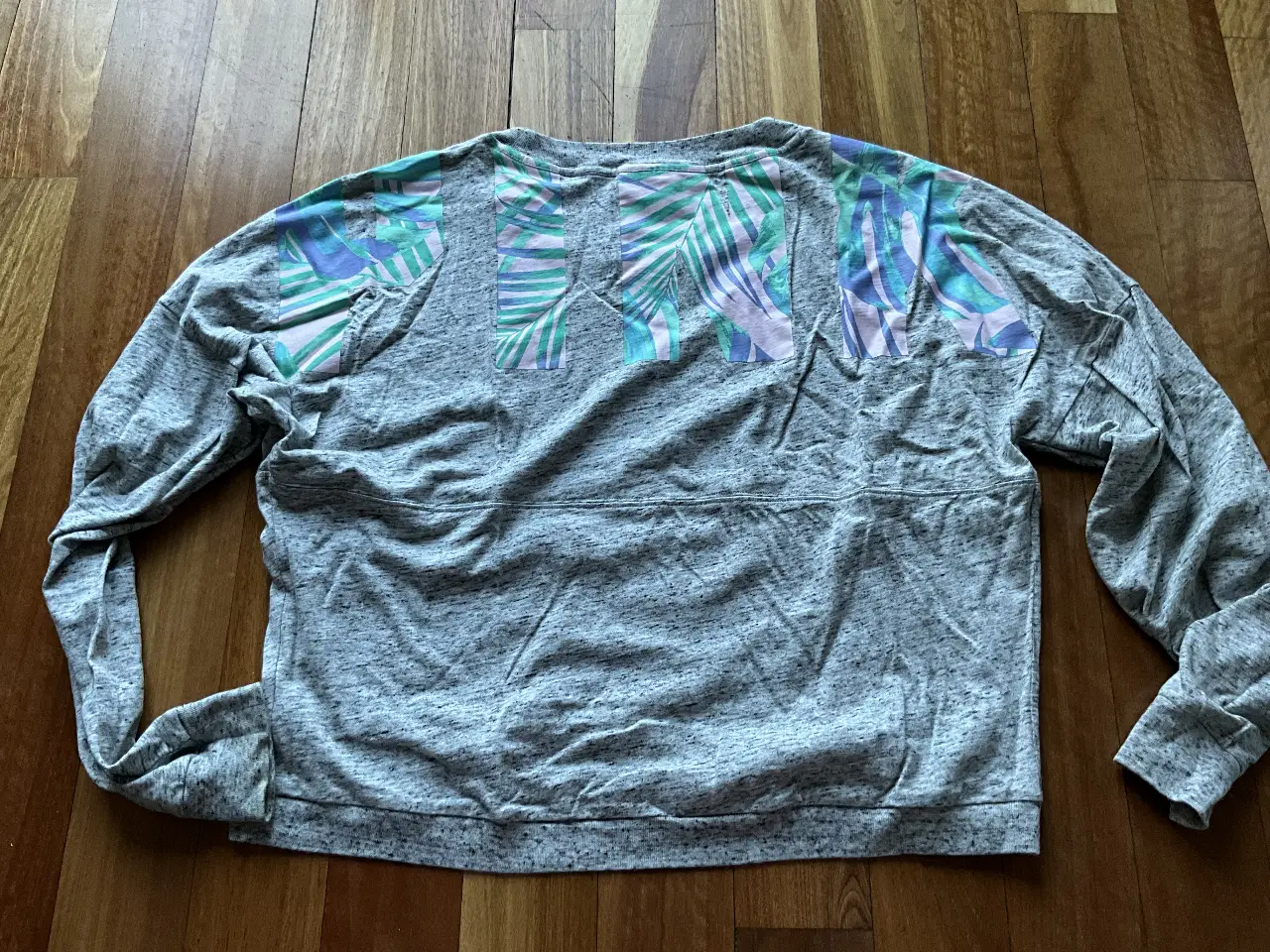Buzo de cuello redondo gris con estampado en la espalda. Ideal para un look casual y cómodo.