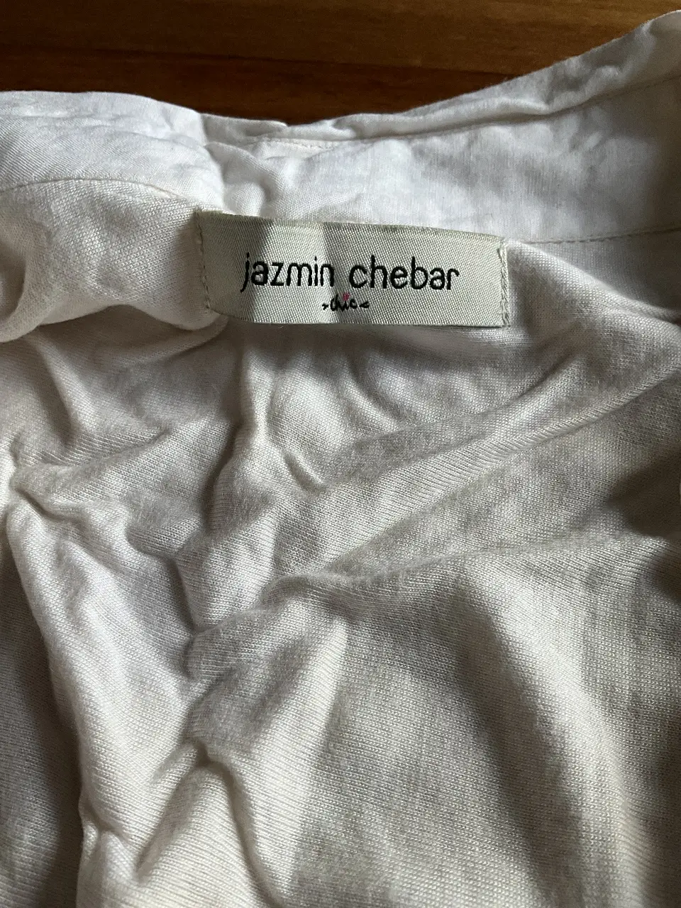 Camisa blanca de la marca Jazmin Chebar, con detalles plisados en el frente. Ideal para un look casual o elegante.