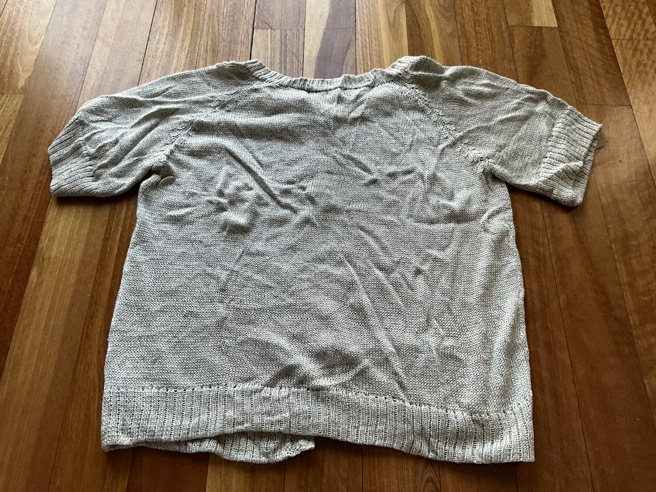 Sweater de punto fino en color gris claro, con mangas cortas y cuello en V. Ideal para un look casual y cómodo.