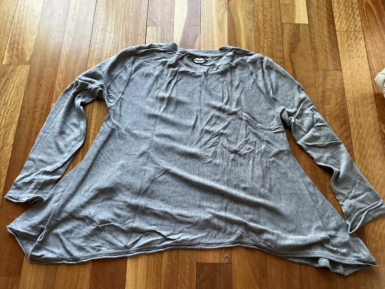 Sweater largo de mujer, color gris, con mangas largas y corte evasé. Ideal para un look casual y cómodo.
