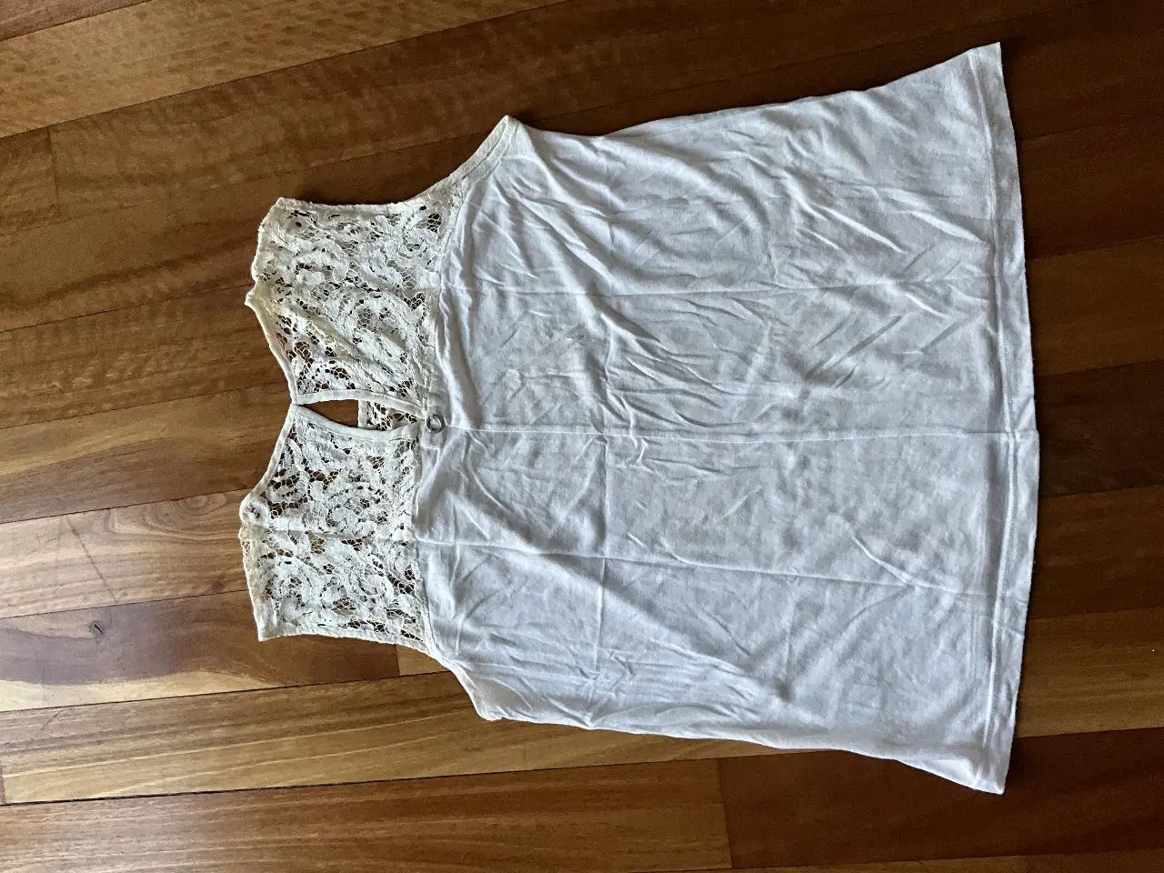 Blusa blanca de mujer con detalles de encaje en la parte superior. Ideal para un look casual y fresco.