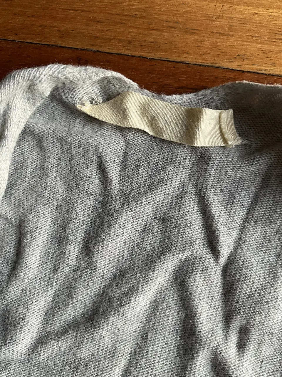 Cardigan de tejido liviano en color gris, con flecos en el borde inferior. Ideal para un look casual y cómodo.