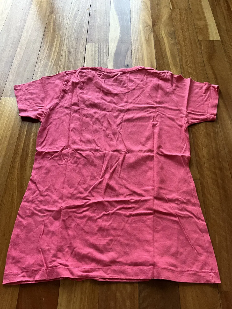 Remera deportiva rosa de la marca Nike, con diseño estampado en el frente. Ideal para actividades físicas o uso casual.