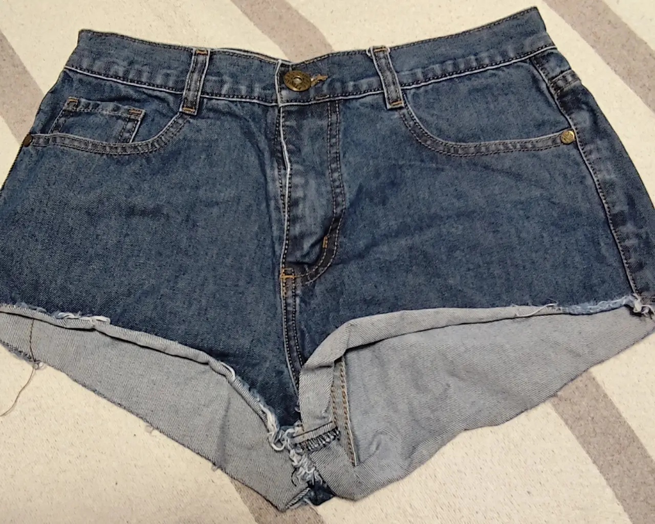Short de jean azul, tiro medio, con detalles de desgaste en los bordes. Ideal para un look casual y fresco.