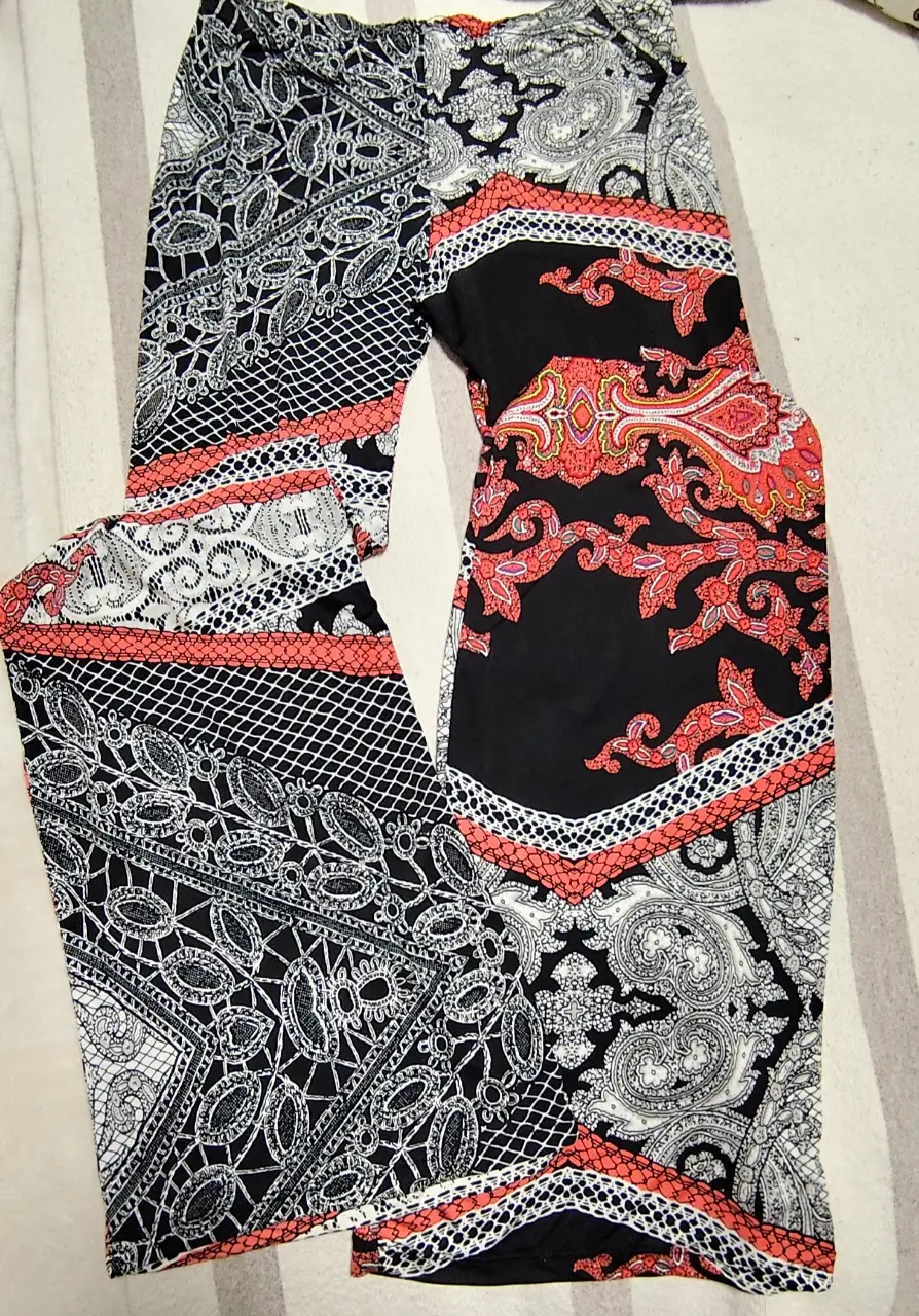 Pantalón suelto con estampado geométrico y floral en blanco y negro, con detalles en rojo. Ideal para un look casual y con estilo.