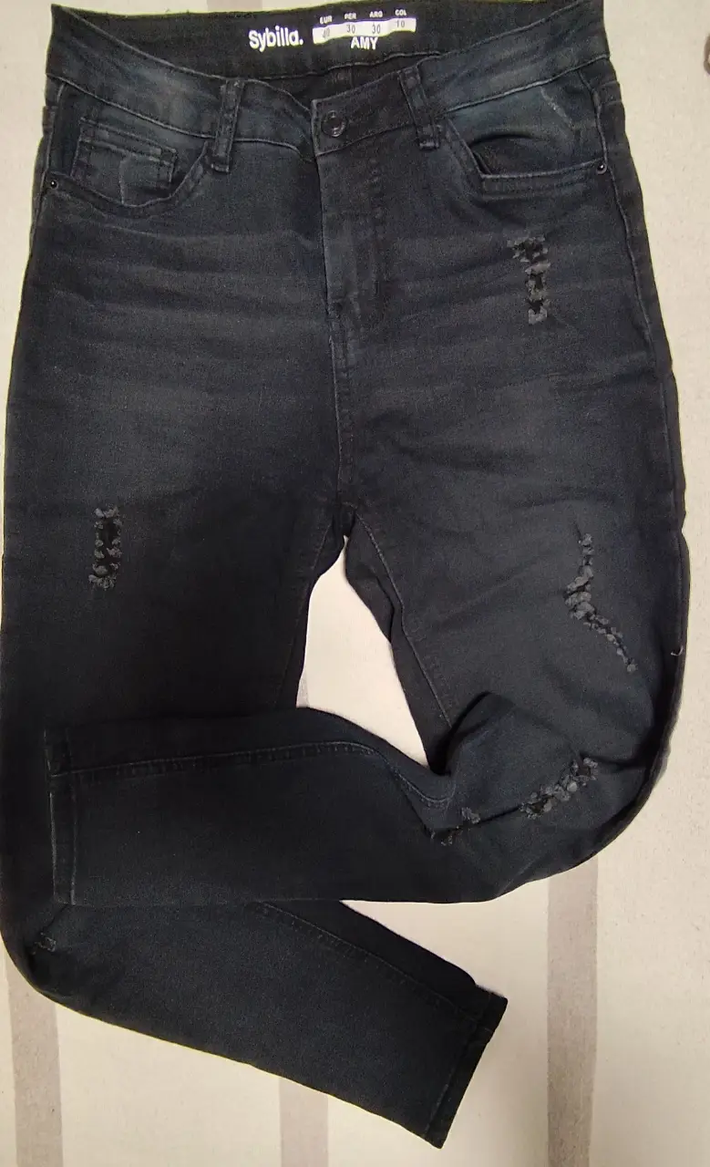 Jeans negro con roturas, tiro medio, ideal para un look casual y moderno. Perfecto para combinar con remeras o camisas.