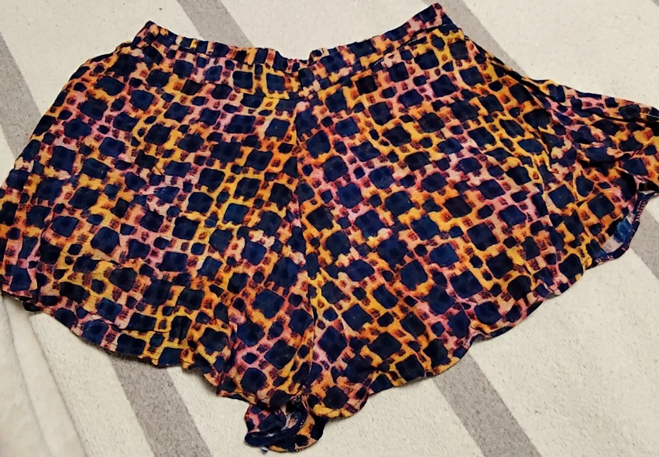 Short de tela con estampado geométrico en tonos azul, amarillo y naranja. Ideal para un look fresco y cómodo.
