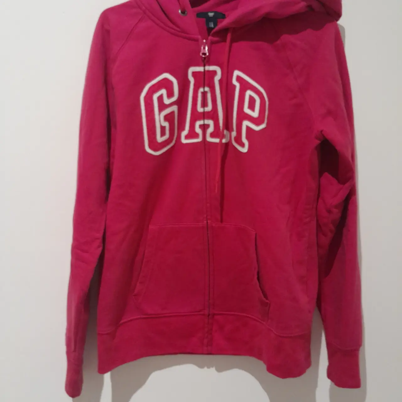 Buzo con cierre de la marca GAP, color rosa, con capucha y bolsillo tipo canguro. Ideal para un look casual y cómodo.