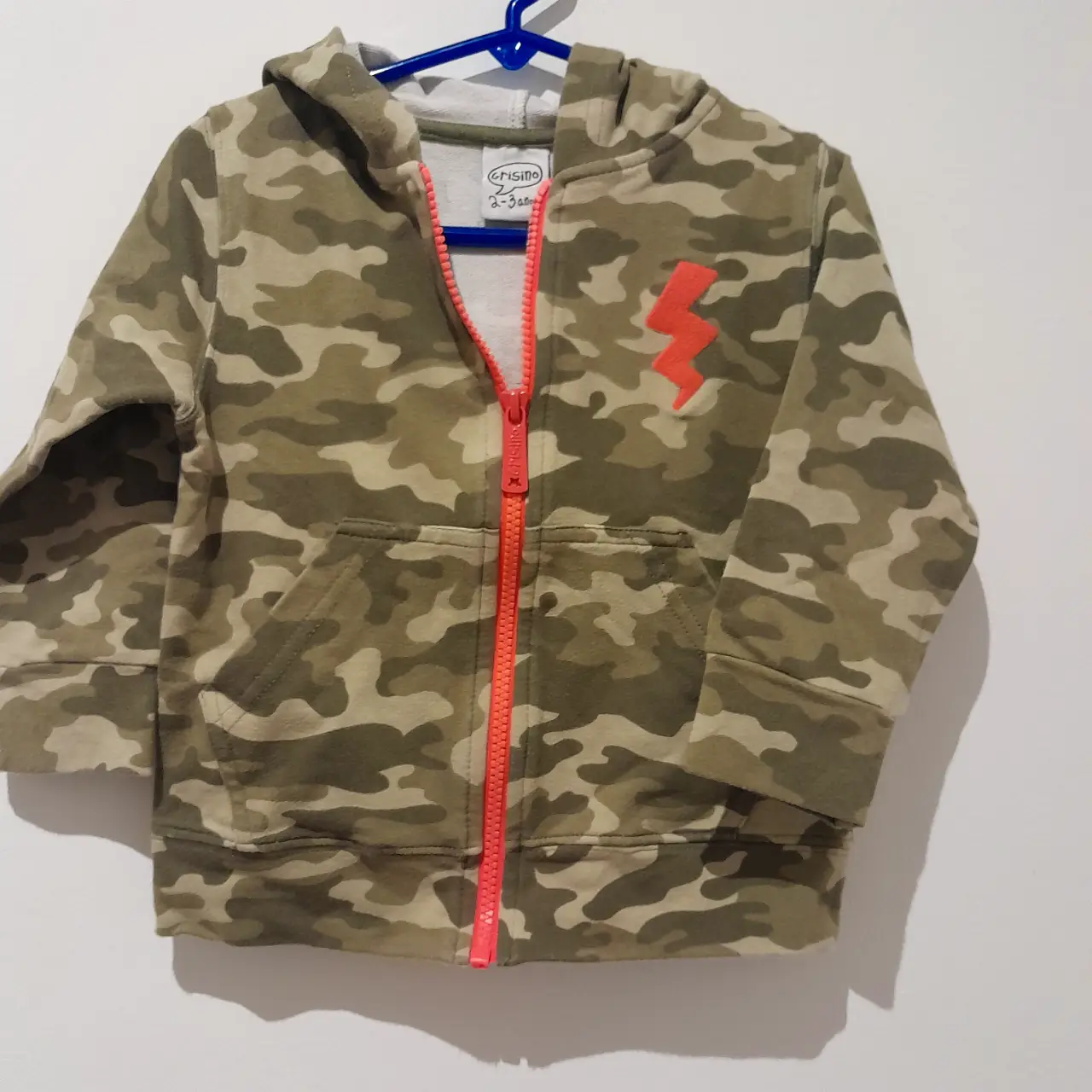 Buzo con cierre para niño, con estampado de camuflaje y un rayo rojo en el pecho. Ideal para un look casual y cómodo.