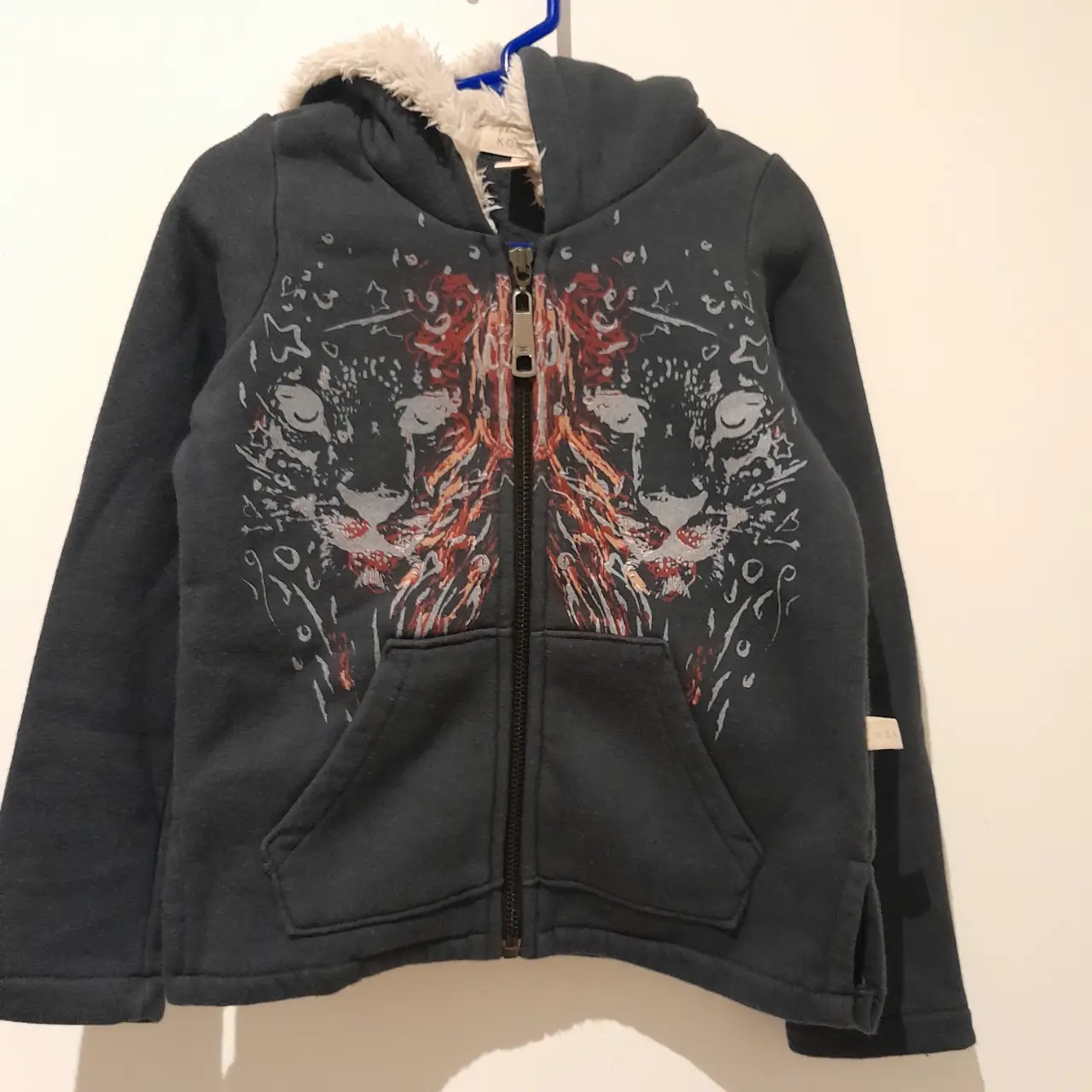 Buzo Kosiuko para niño, color gris oscuro con un estampado muy canchero. Posee capucha con forro de piel sintética y bolsillos delanteros. Ideal para el invierno.