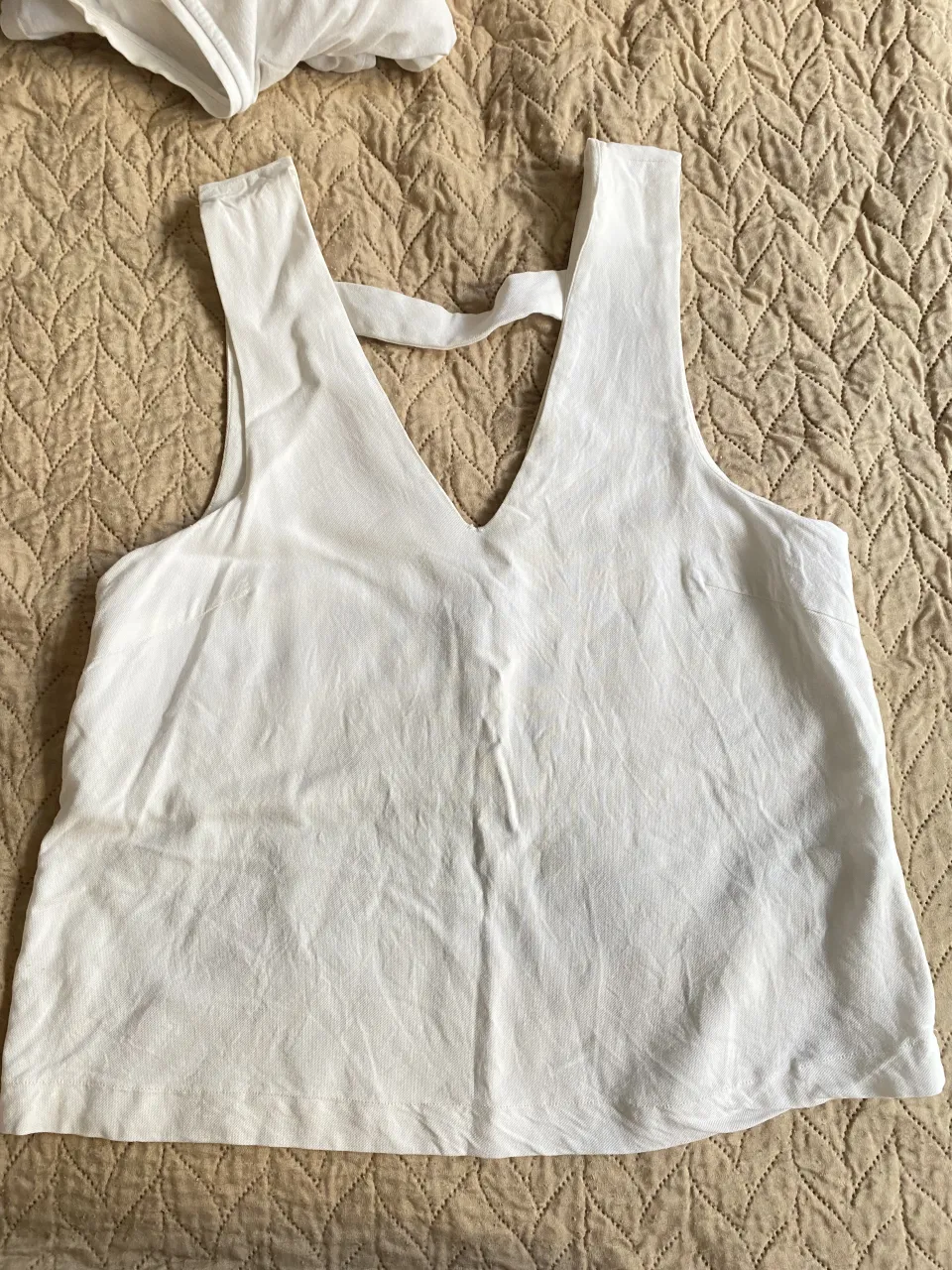 Top blanco escotado con tiras cruzadas en la espalda. Ideal para un look casual o de fiesta.