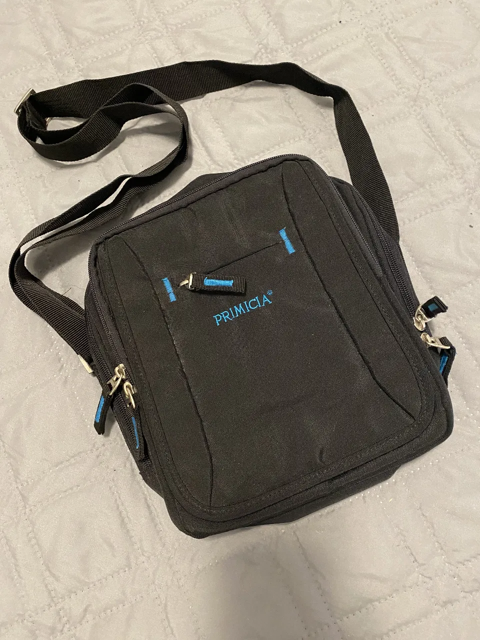 Bandolera negra PRIMICIA, ideal para llevar tus pertenencias de forma segura y cómoda. Cuenta con un compartimento principal y bolsillos adicionales para organizar tus objetos. Perfecta para el día a día.