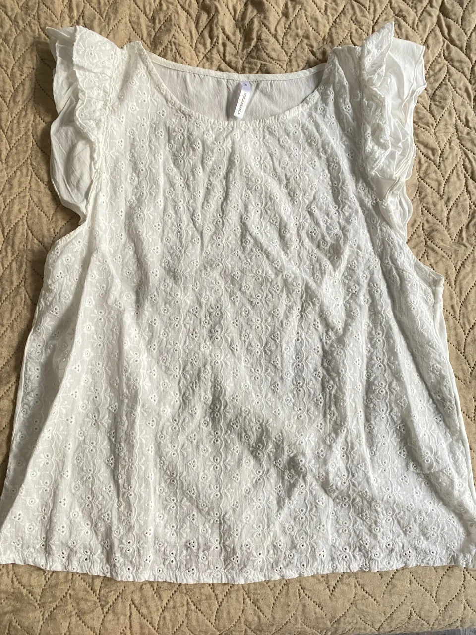 Blusa blanca de algodón con delicados bordados y detalles de puntilla en mangas y ruedo. Diseño fresco y romántico, ideal para días cálidos. Perfecta para un look casual o semi-formal.