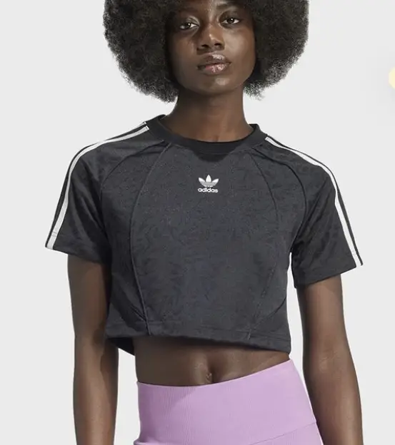 Remera deportiva crop de mujer, negra con detalles de diseño y las icónicas tres tiras blancas de Adidas en las mangas. Ideal para entrenar con estilo. súper cómoda. NUEVA