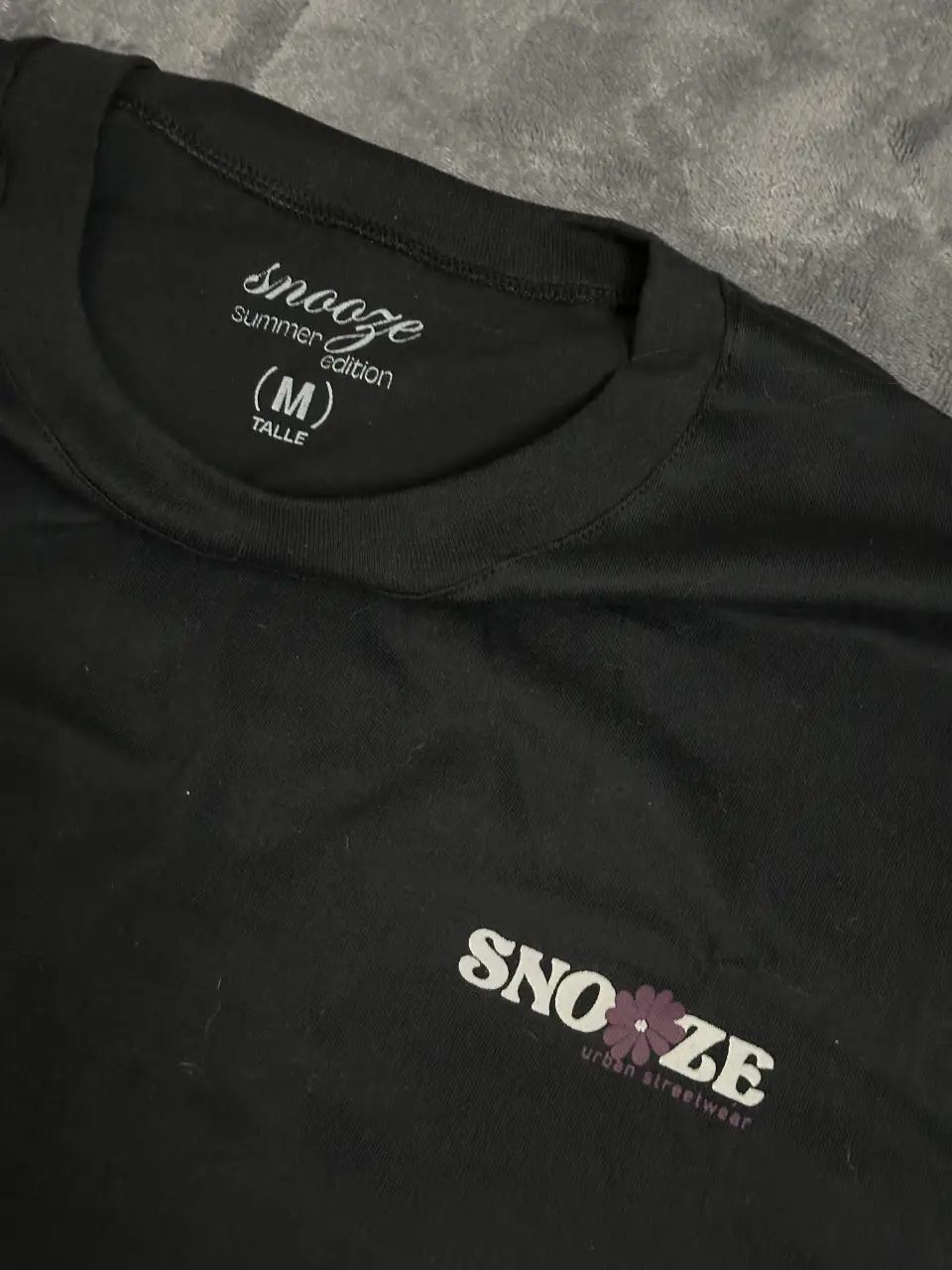 Remeron negro de manga corta con estampado "Snooze Summer Edition" y logo floral.  En la espalda, estampado "Vacations" con diseño floral.