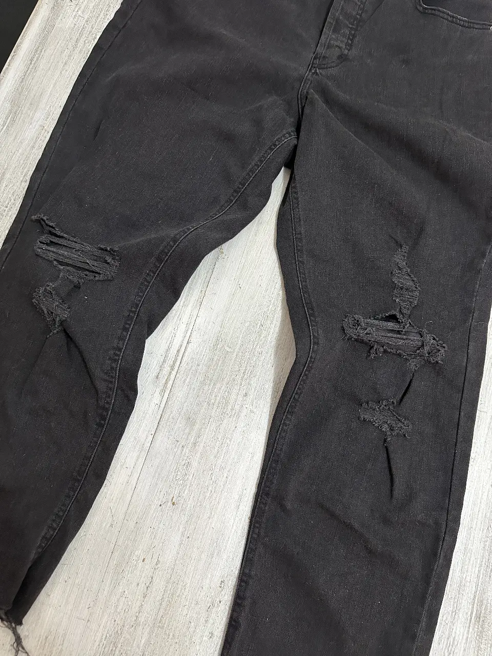 Jeans negro de corte recto con roturas en las rodillas. Tiro alto, ideal para un look casual y moderno. Talle 44