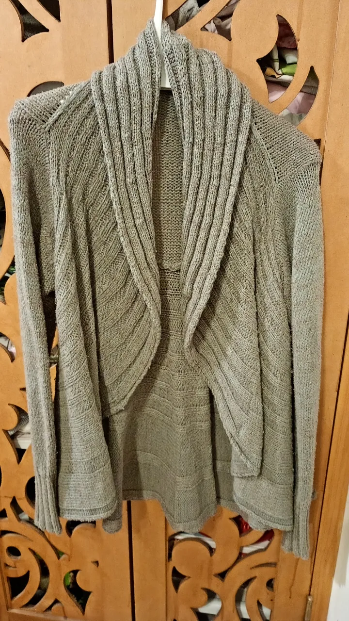 Cardigan de tejido grueso en color gris. Diseño con cuello amplio y solapas, ideal para un look casual y abrigado. Perfecto para combinar con diferentes outfits.