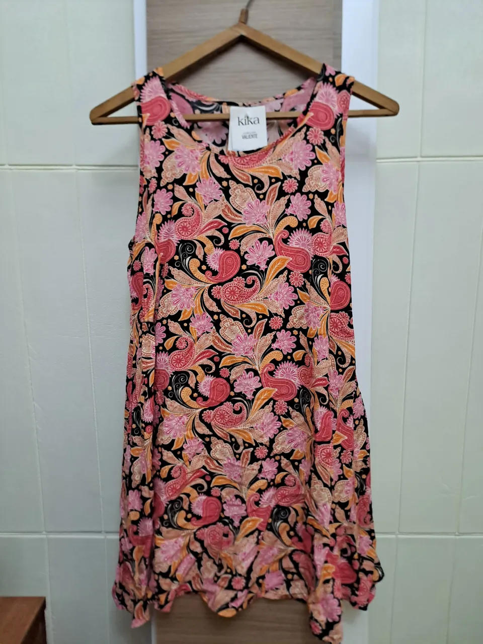 Vestido  estampada con flores y detalles en tonos rosas, naranjas y negros. Posee cuello redondo y es sin mangas.