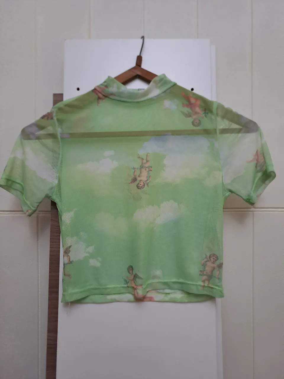 Remera manga corta de red con estampa de nubes y querubines. Cuello alto.