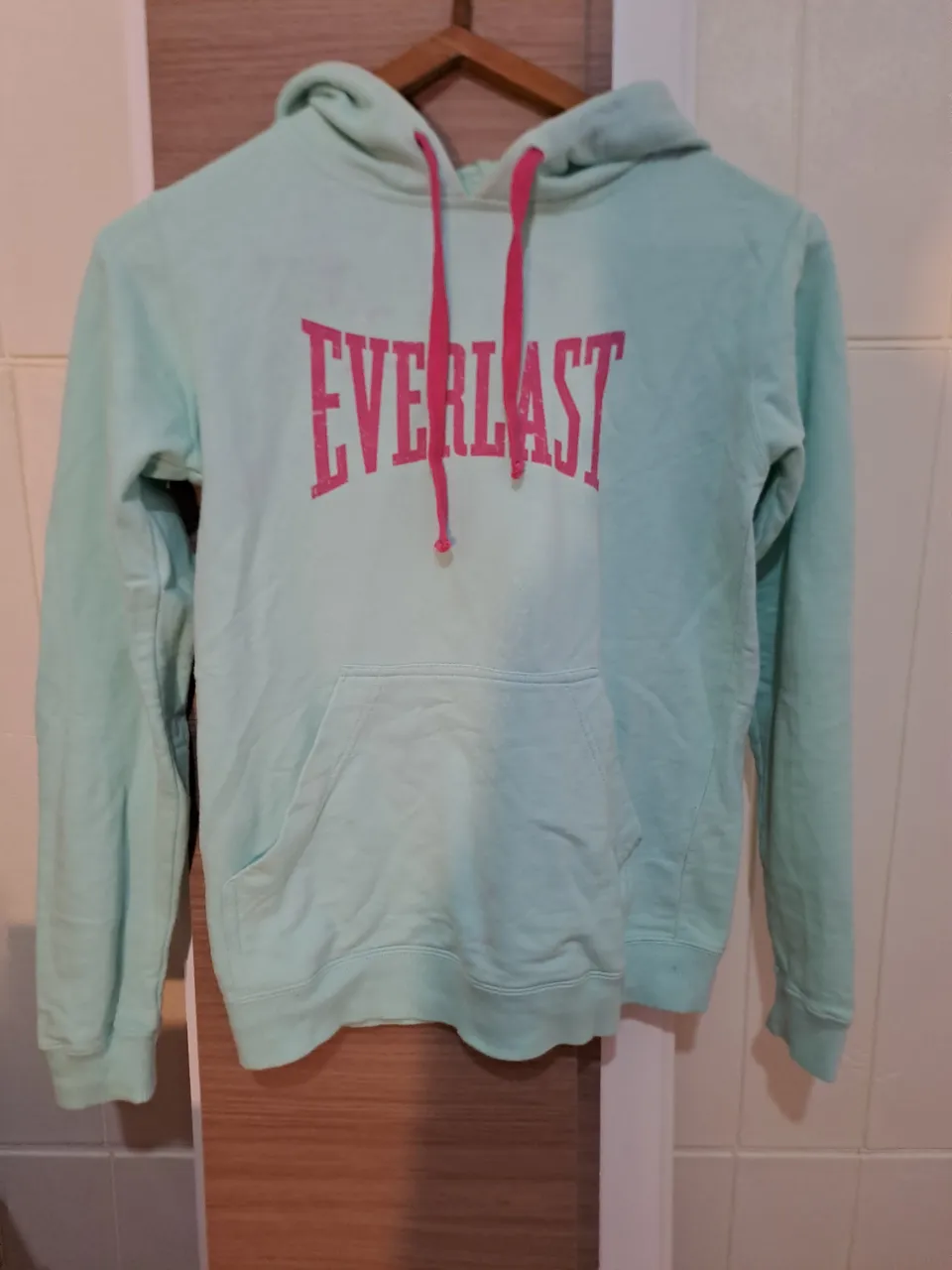 Buzo con capucha y cordones fucsia. Estampa de la marca en color fucsia en el frente. Bolsillo canguro.