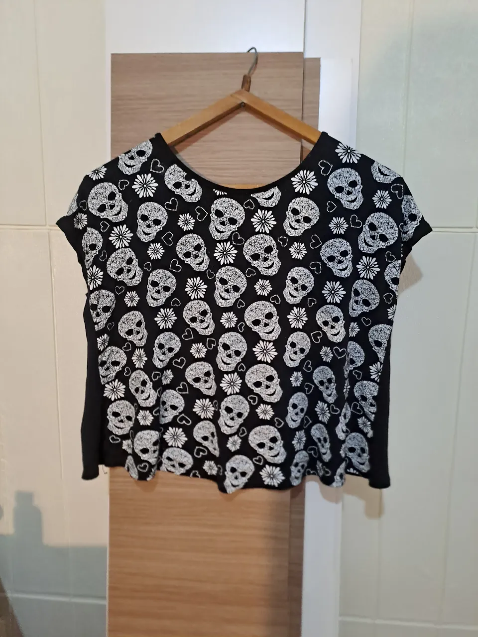 Remera negra con estampa de calaveras y flores blancas. Diseño crop. con espalda abierta fina y femenino