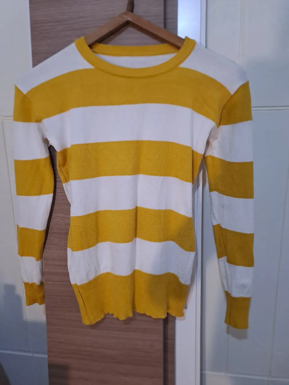 Sweater de rayas horizontales amarillas y blancas. Manga larga y cuello redondo.