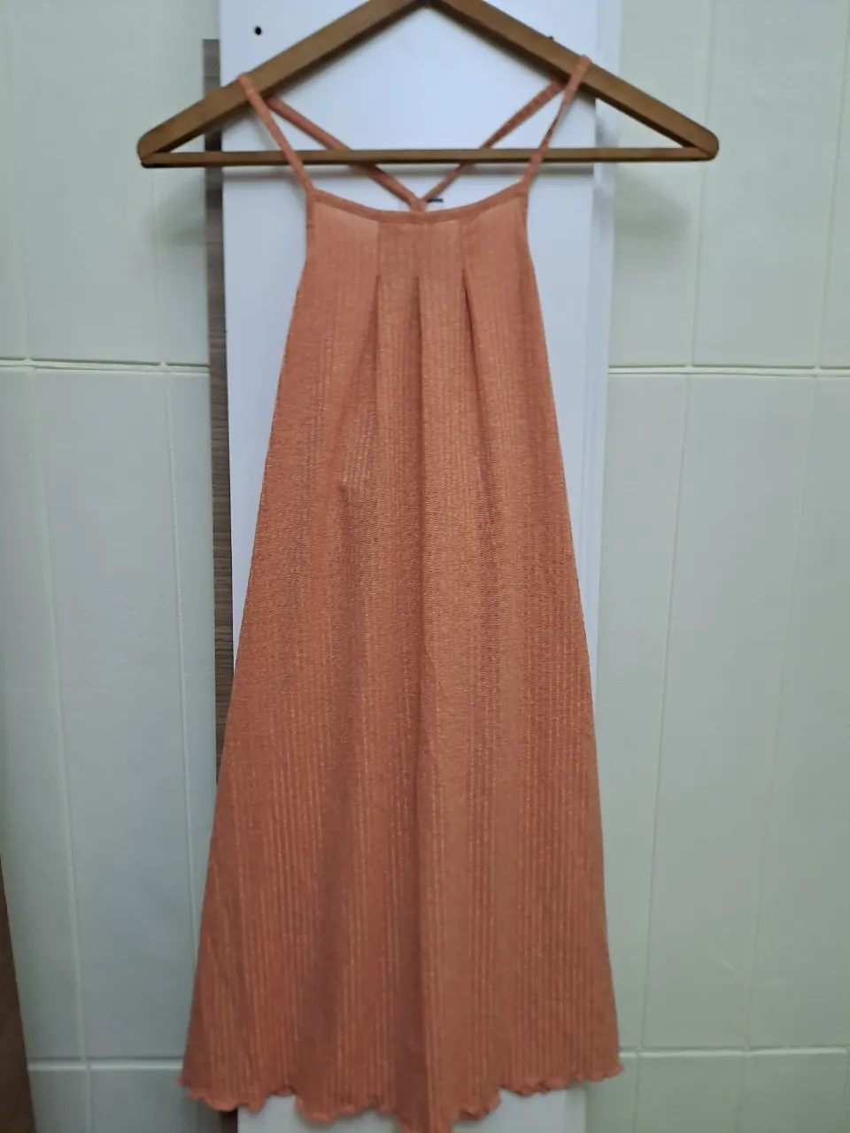 Vestido naranja con tiras finas cruzadas en la espalda y detalle de pliegues en el busto. Posee un borde inferior con ondas.