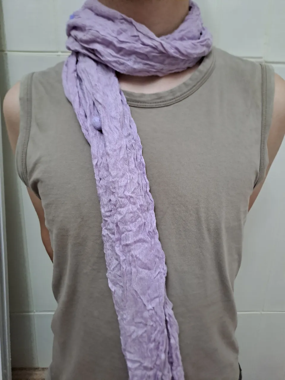 Pañuelo de tela color lila con textura arrugada y detalles de pompones.