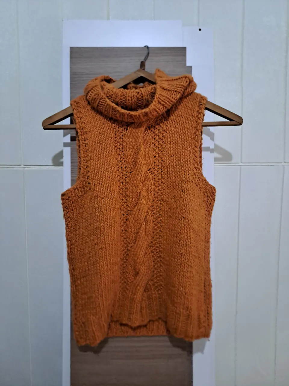 Sweater tejido sin mangas, color naranja. Cuello alto tipo polera con textura de trenzas en el frente.