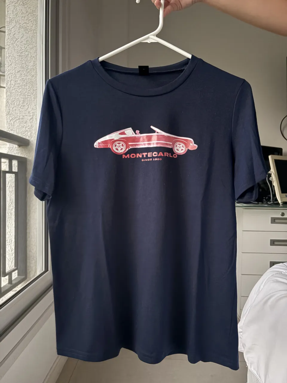 Remera azul marino con estampa de auto deportivo rojo y blanco en el frente. La estampa dice "MONTECARLO" y "SINCE 1980".