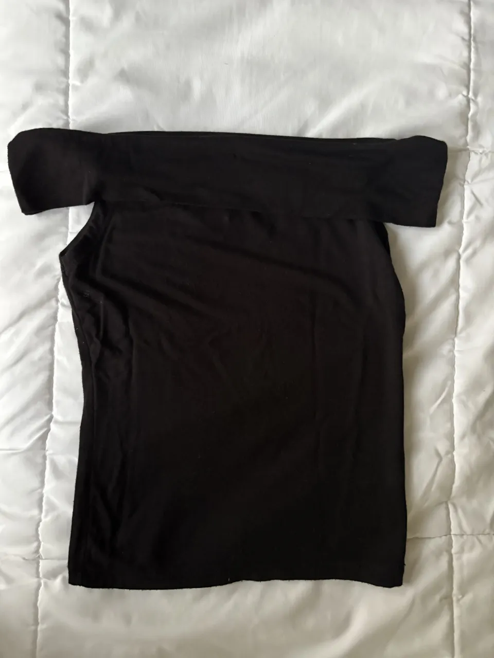 Remera negra de manga corta, escote descubierto.