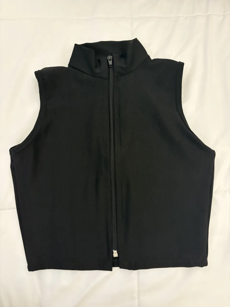 Musculosa negra con cuello alto y cierre completo al frente.