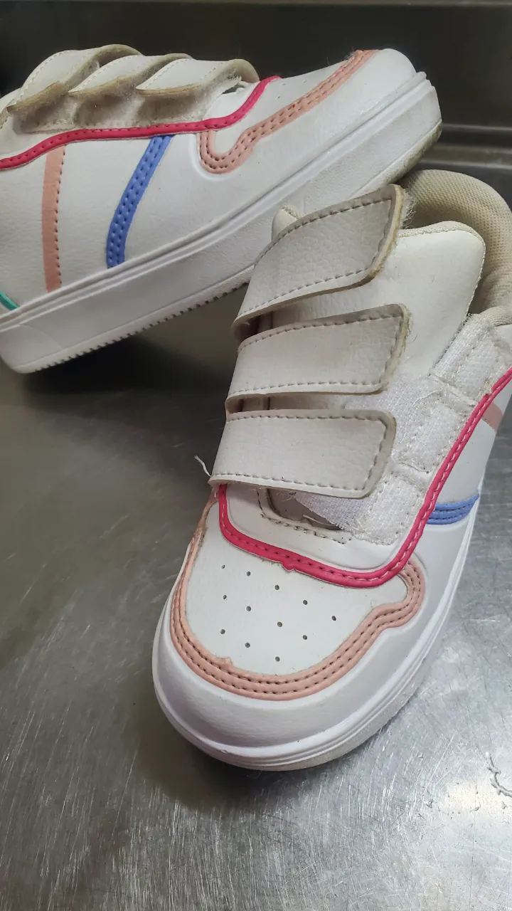 Zapatillas blancas con detalles en rosa, azul y verde. Tienen tres abrojos para ajustar.
