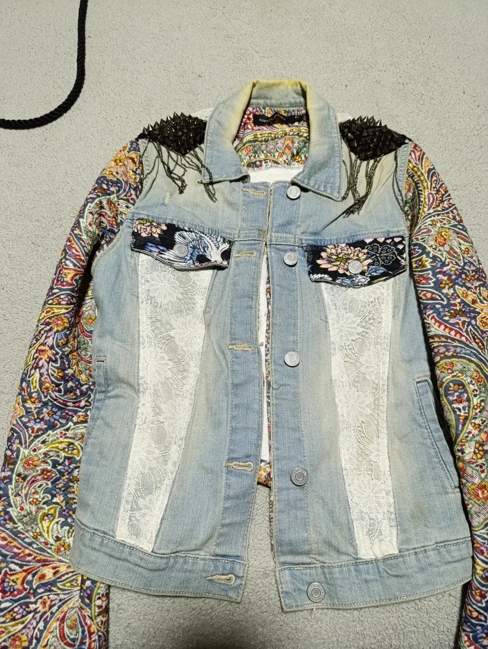 Campera de jean gap intervenida con chaqueta cuesta blanca y detalles únicos. Posee apliques de encaje, tela estampada y tachas en los hombros. Un diseño bohemio y con estilo.