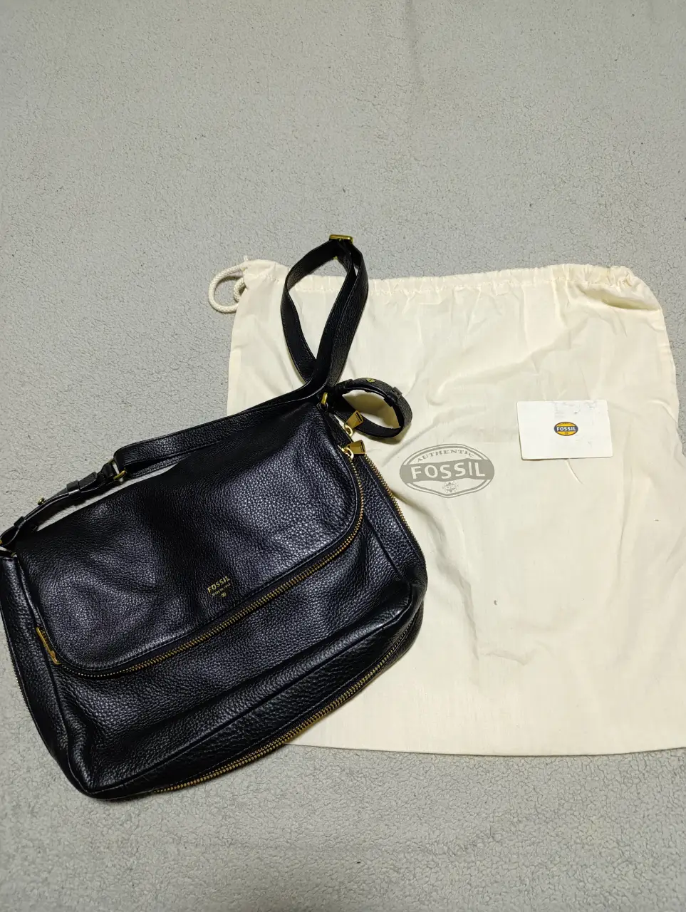 Cartera bandolera de cuero negro de la marca Fossil, con cierre y correa ajustable. Incluye bolsa protectora y etiqueta. 35cm x 25cm bolsillo interno, división y bolsillo exterior 