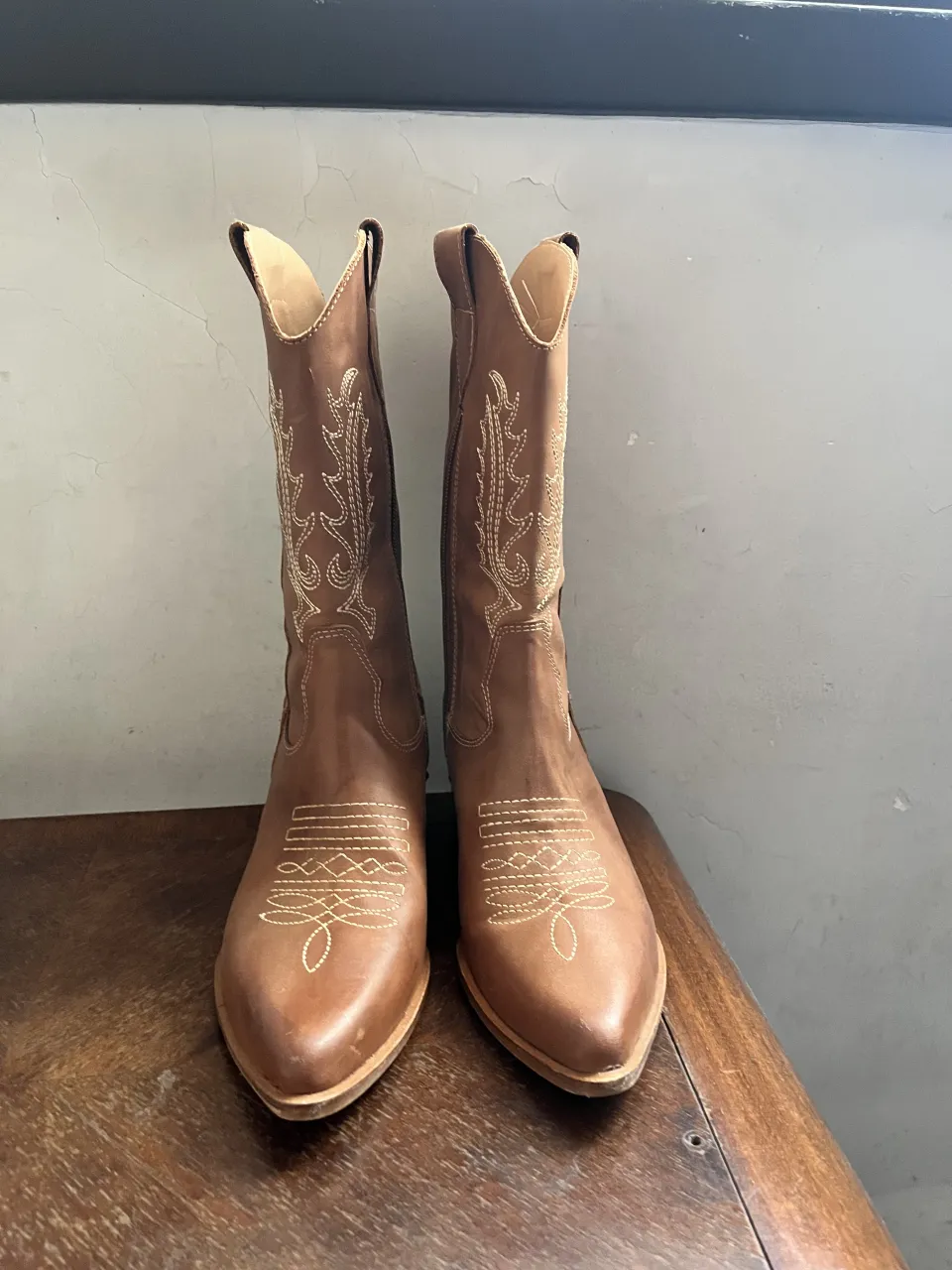 Botas de cuero color marrón con bordados blancos en la caña y en la punta. Cierre lateral.