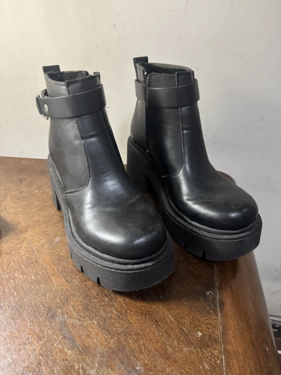 Botas negras de cuero sintético con plataforma y hebilla. Tienen cierre lateral y suela track.