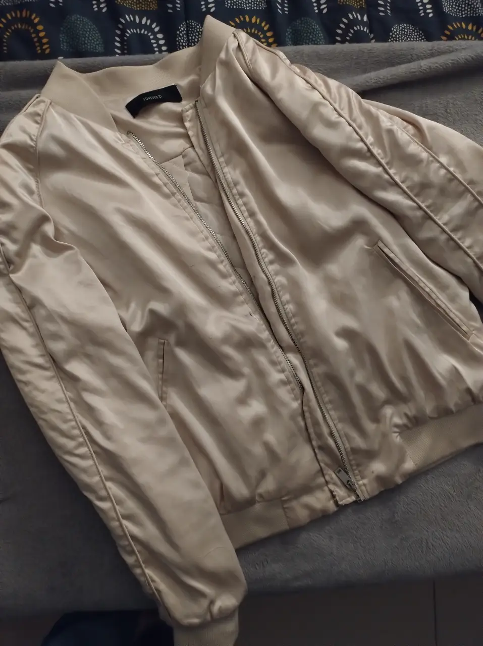 Campera bomber de satén color crudo, con cierre y bolsillos. Ideal para un look casual y elegante. tiene unas mini manchitas al lado del cierre.
