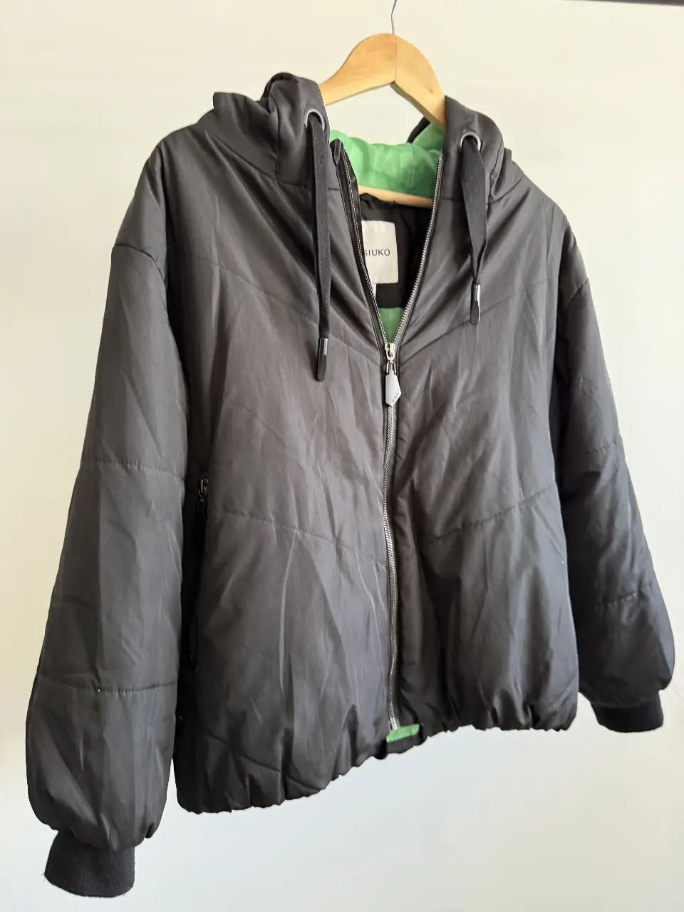 Campera negra con capucha y forro verde. Ideal para el invierno, con cierre y bolsillos. Talle XS de la marca Kosiuko.