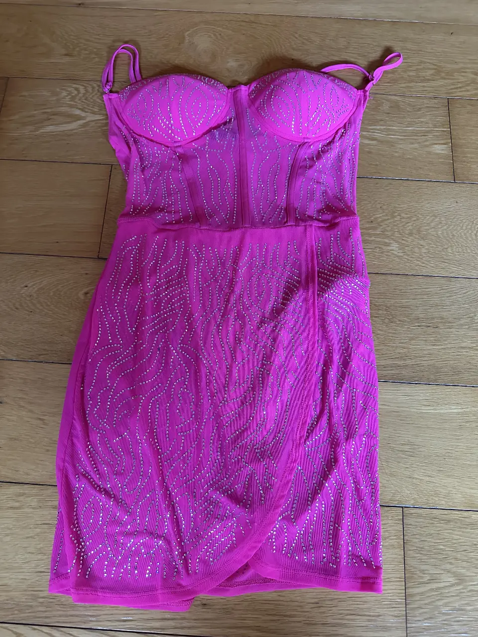 Vestido mini fucsia con detalles de strass marca Toqe. Ideal para fiestas y eventos especiales. Diseño ajustado y escote pronunciado.