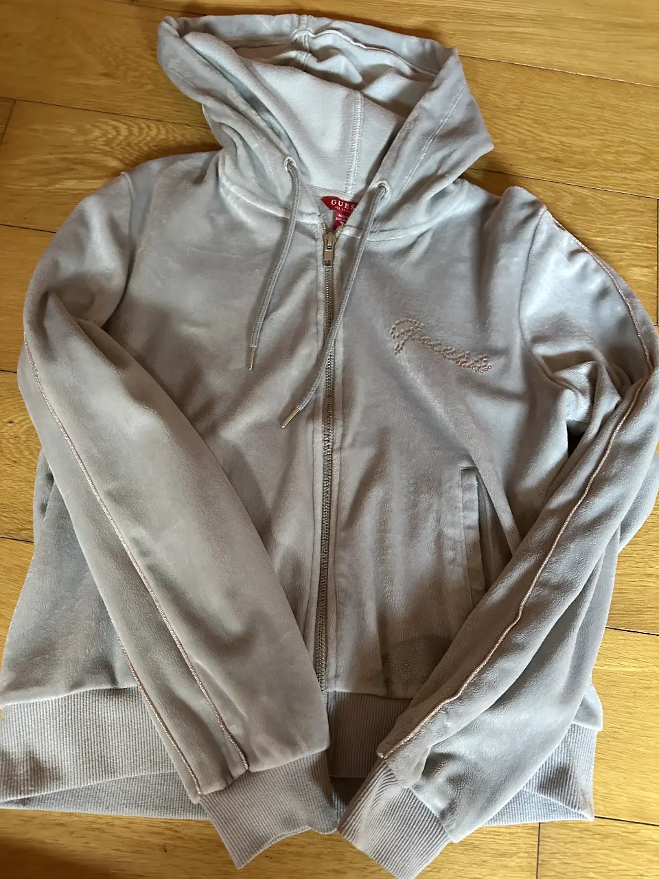 Buzo de plush con cierre Guess de mujer, color gris, con capucha y detalles de strass. Talle S.