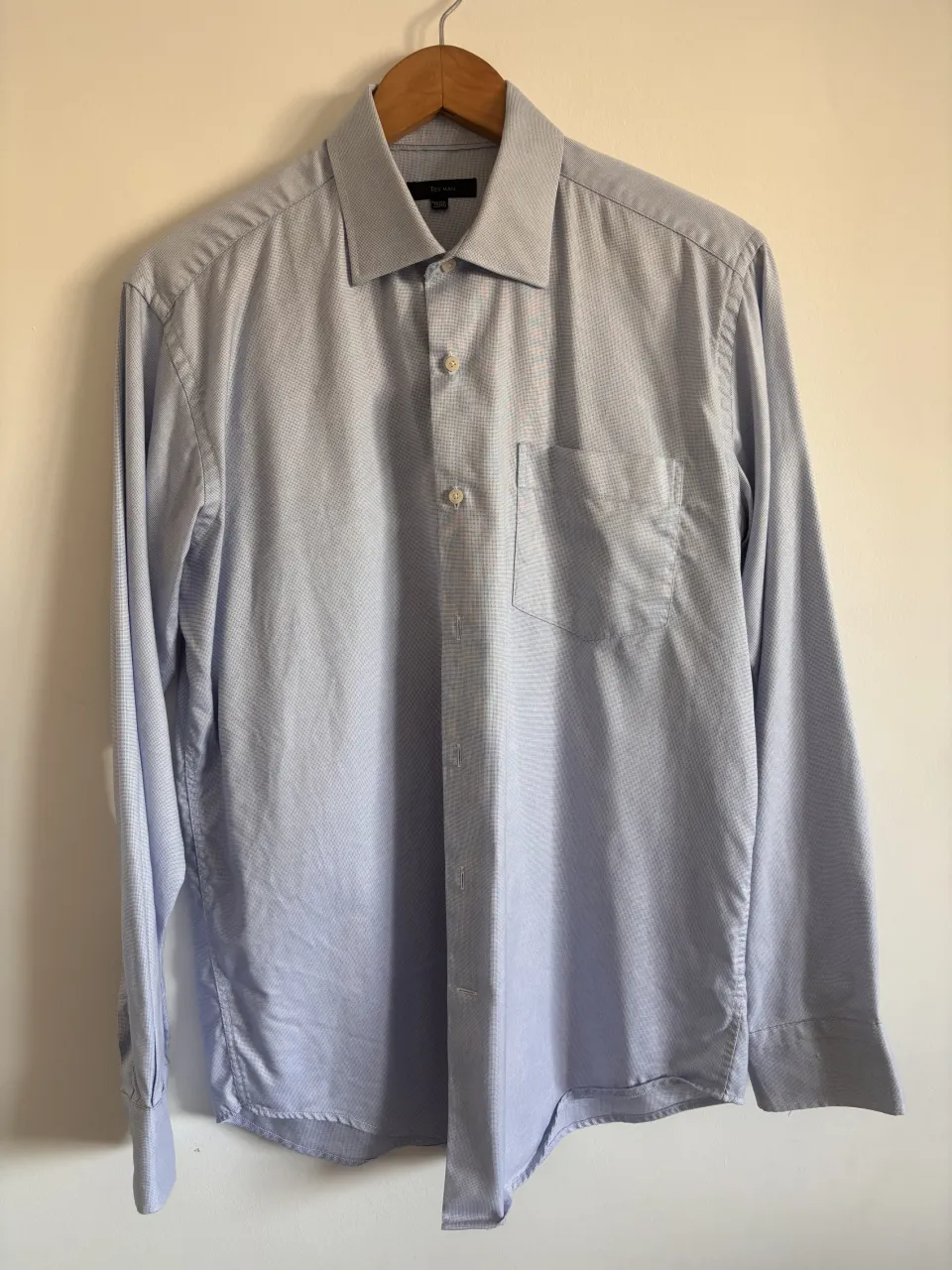 Camisa de vestir manga larga, ideal para un look formal o de trabajo. Posee un bolsillo en el pecho y botones al tono.